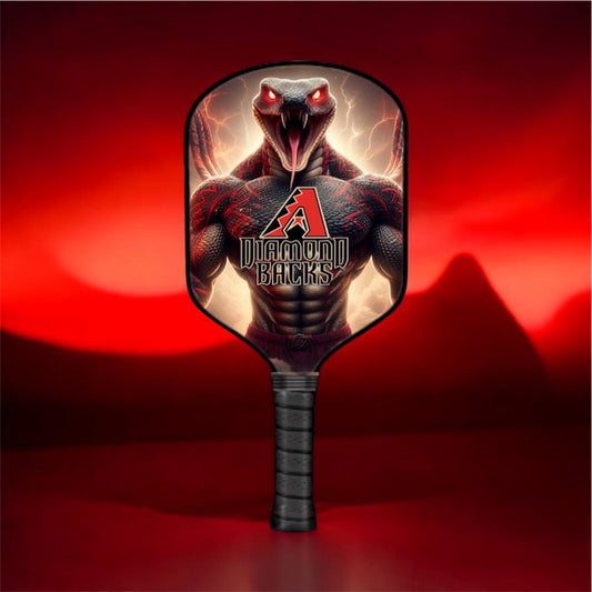 A pickleball paddle featuring a graphic of a muscular black snake with glowing red eyes and lightning, with the text 'Diamondbacks' and a red 'A' logo. The paddle has a black wrapped handle and is set against a dark red background with a mountain silhouette.