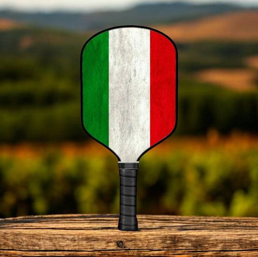 Pickleball paddle with Italian flag design on a wooden surface with a blurred natural background