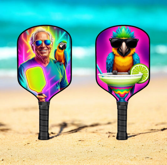 Two colorful pickleball paddles with jimmy buffet artistic designs on a beach background
