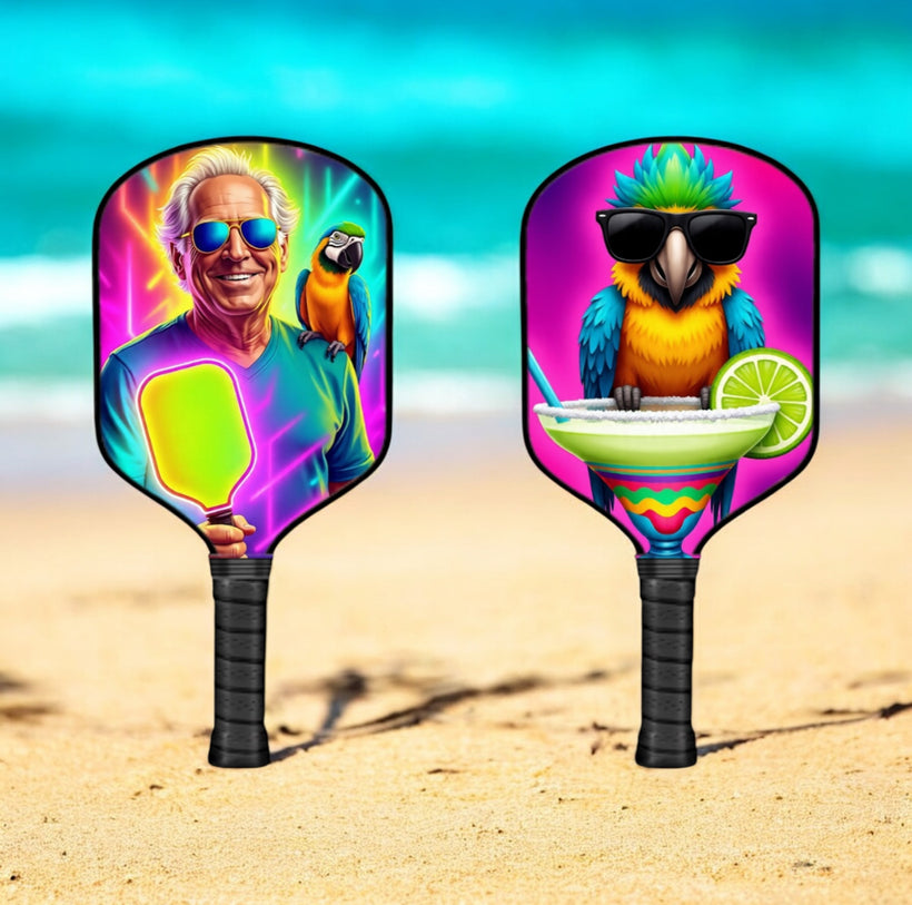 Two colorful pickleball paddles with jimmy buffet artistic designs on a beach background