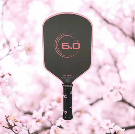 Pickleball paddle with '6.0' branding against a cherry blossom background