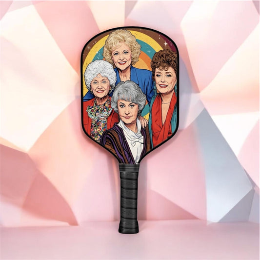 A pickleball paddle featuring an illustrated portrait of the four Blingring sisters from The Golden Girls, set against a pink and white geometric background.